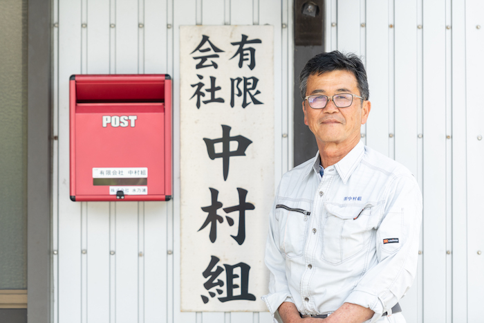 会社の看板と並ぶ男性